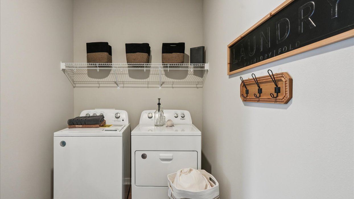 Dedicated laundry room with built-in shelving and utility connections.
