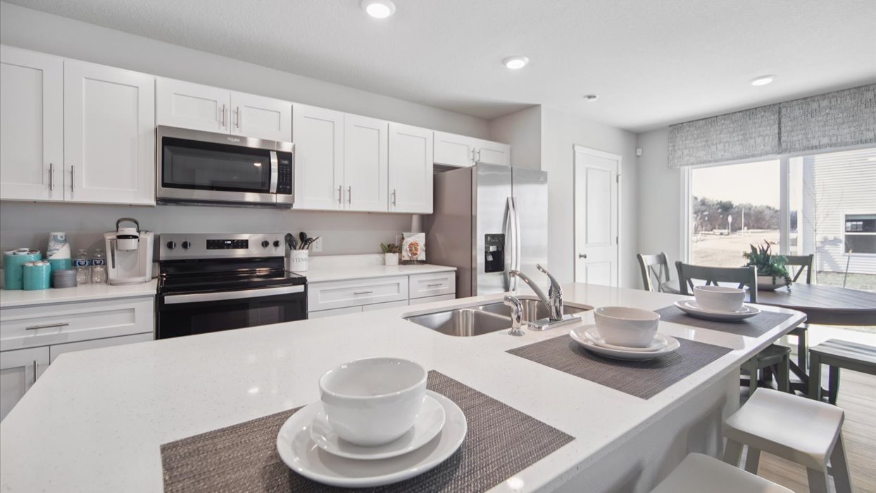 Kitchen with stainless steel appliances, quartz countertops, and white cabinetry