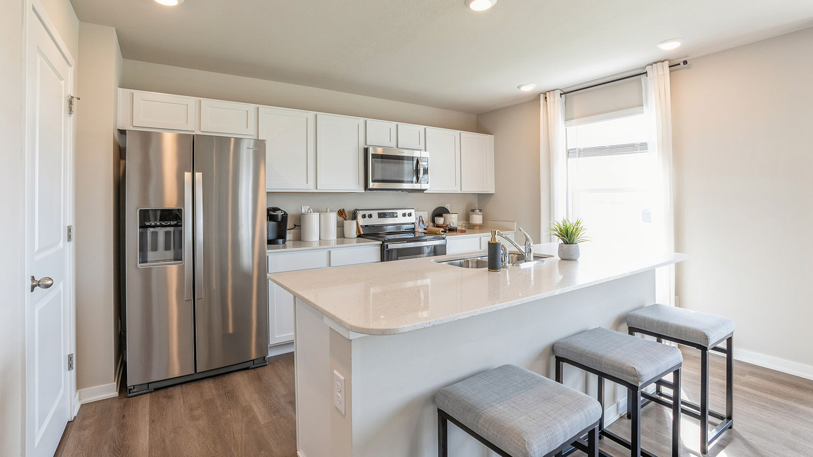 Kitchen with stainless steel appliances, quartz countertops, and white cabinetry