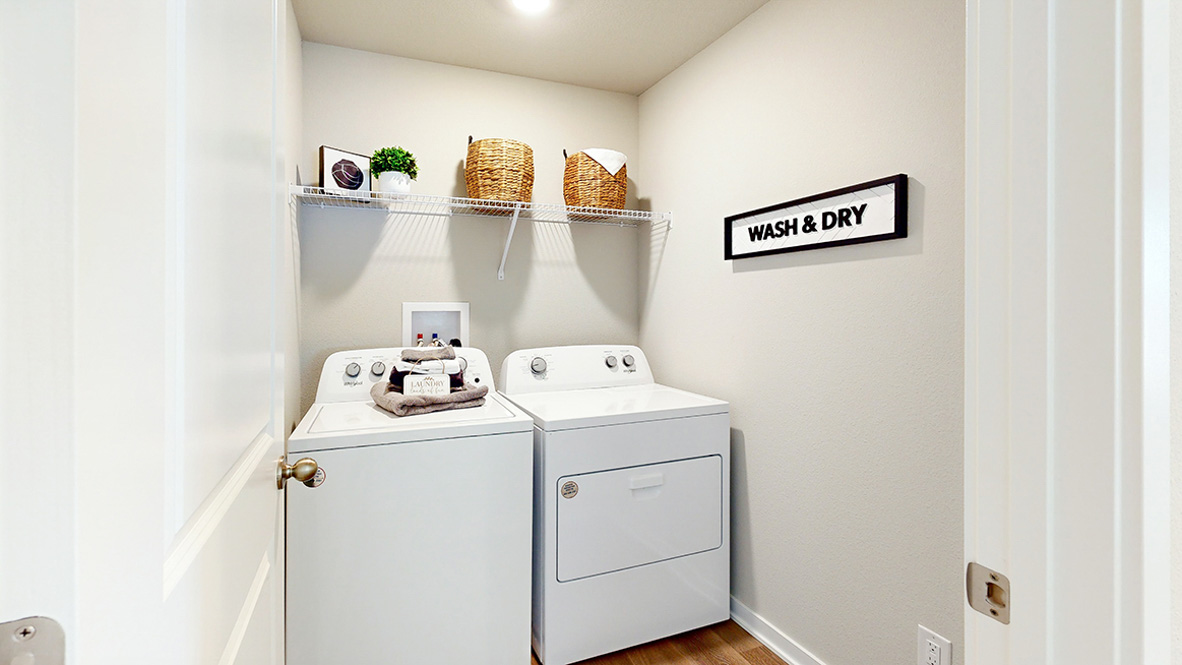 Dedicated laundry room with built-in shelving and utility connections.
