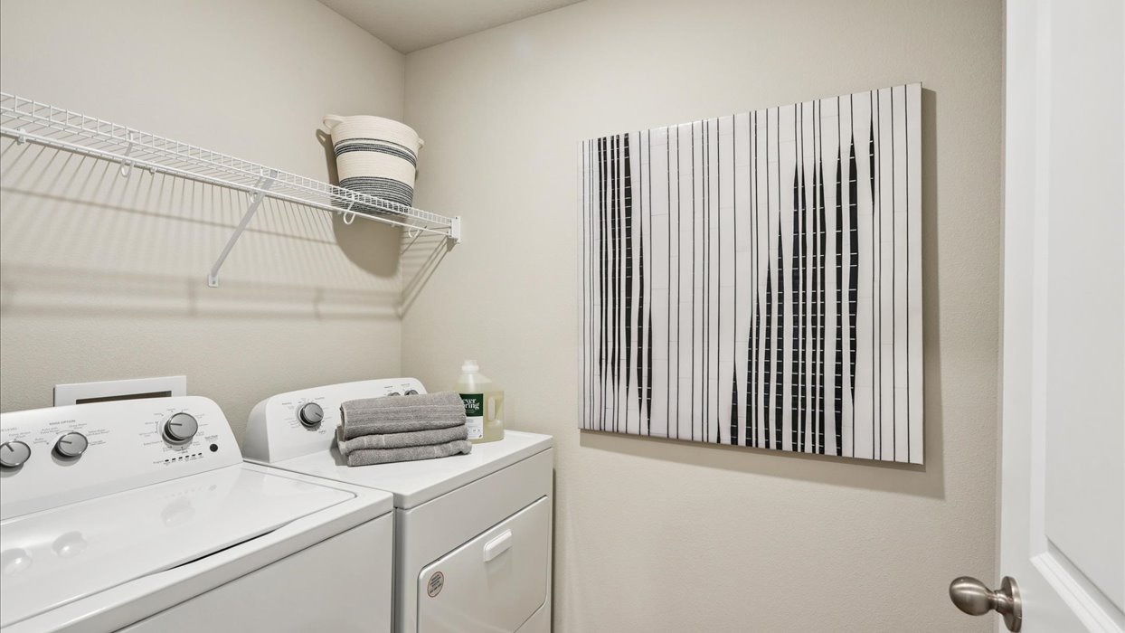 Dedicated laundry room with built-in shelving and utility connections.