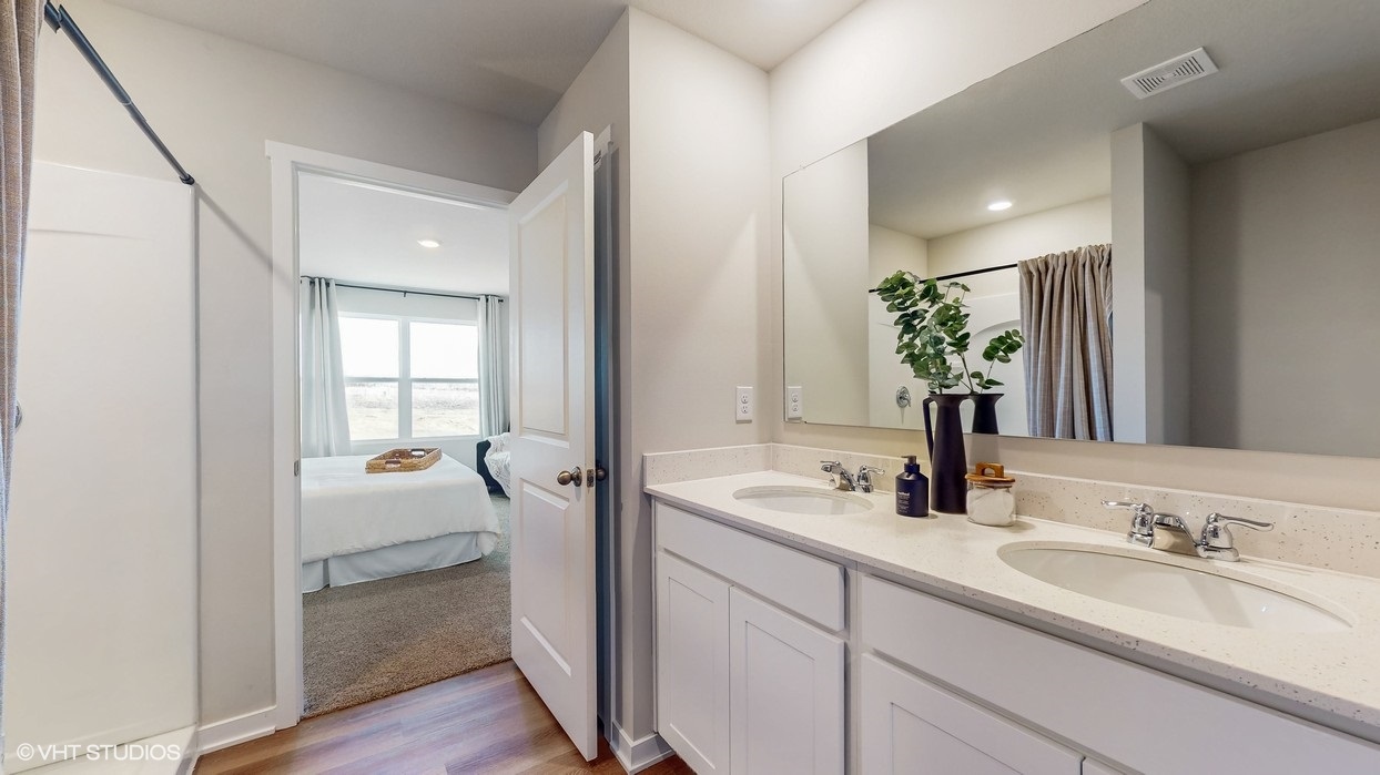 Spacious primary bathroom featuring dual vanities, modern fixtures, and a walk-in shower.