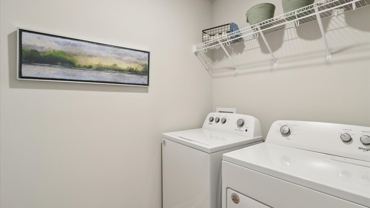 Dedicated laundry room with built-in shelving and utility connections.