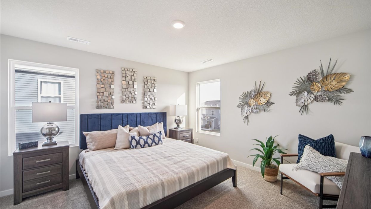 primary bedroom with large white bed and chair