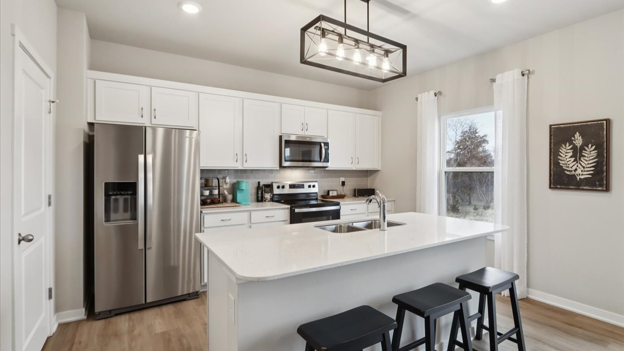 Kitchen with stainless steel appliances, quartz countertops, and white cabinetry