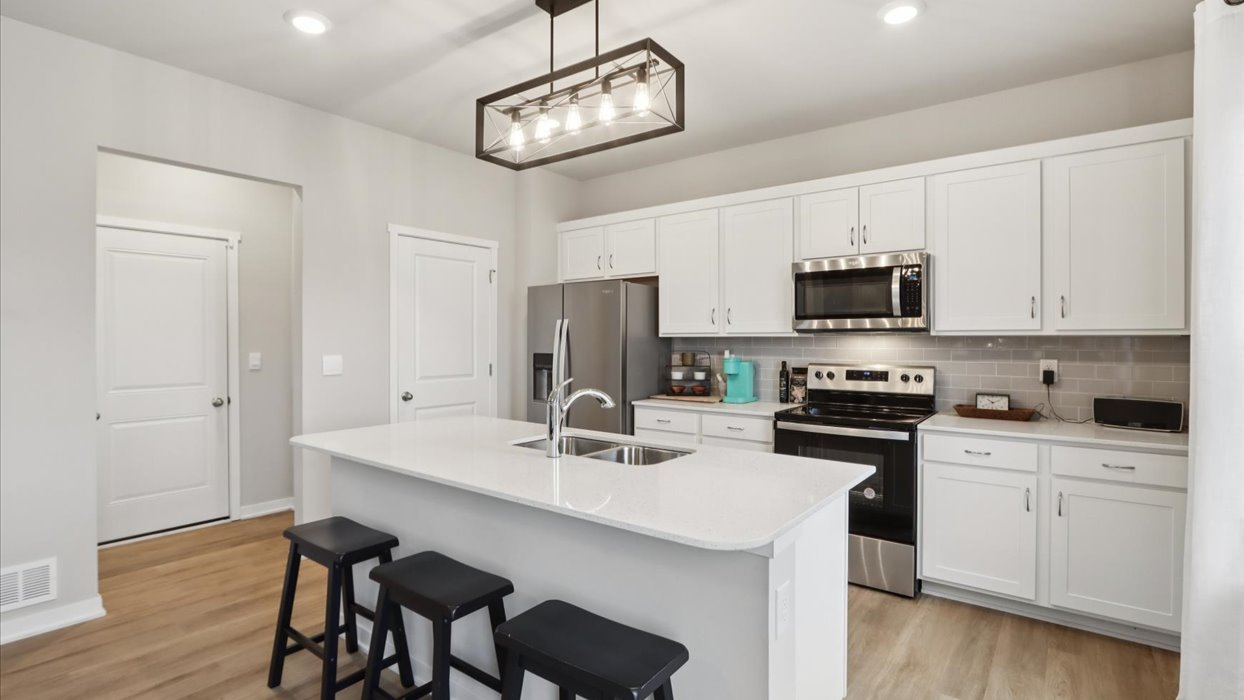 Kitchen with stainless steel appliances, quartz countertops, and white cabinetry