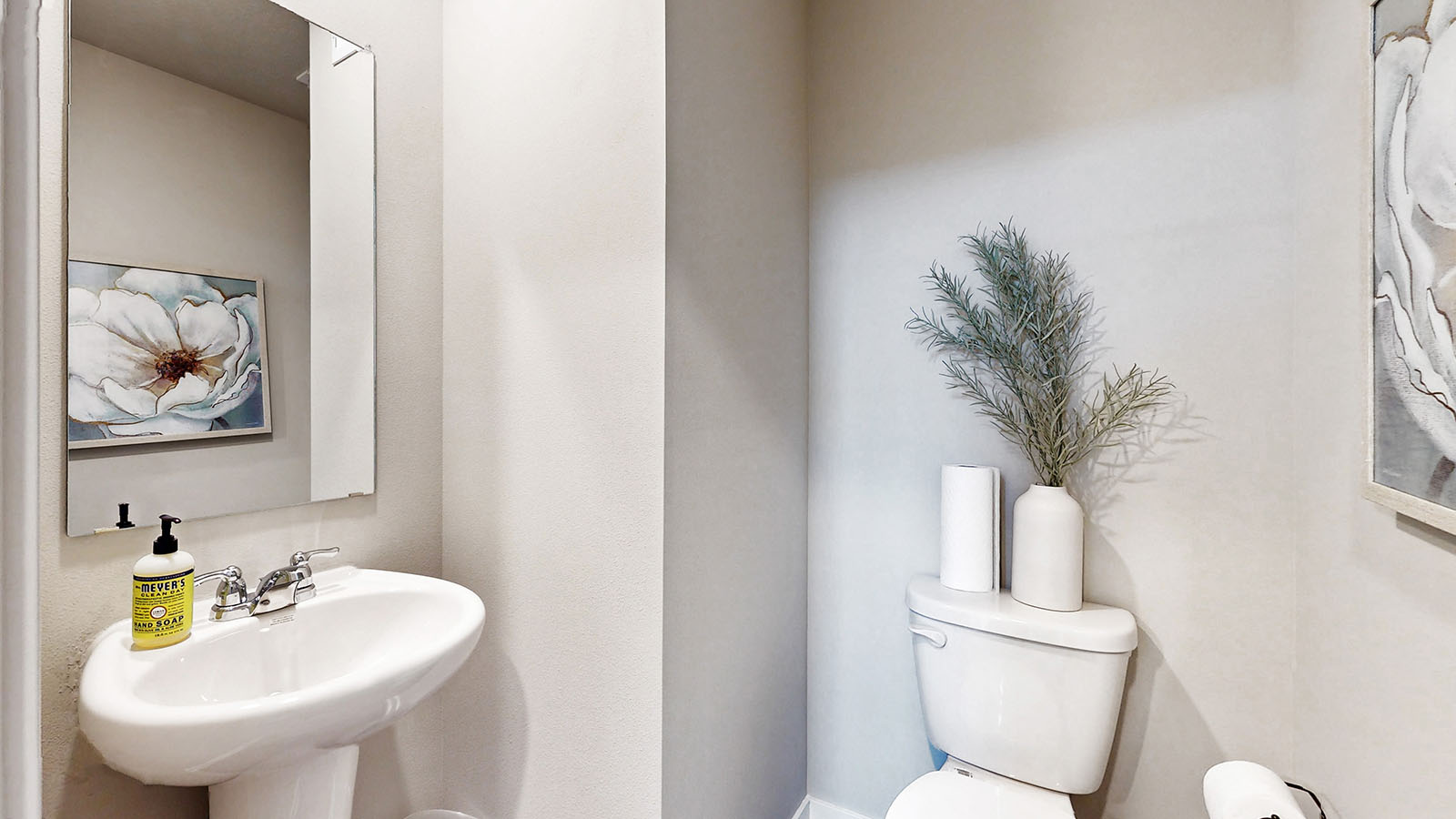 Half bath with hallway door open, pedestal sink, mirror, and stylish polished faucet on main level