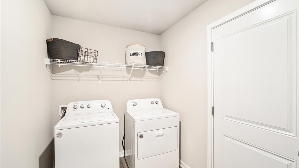 Dedicated laundry room with built-in shelving and utility connections.