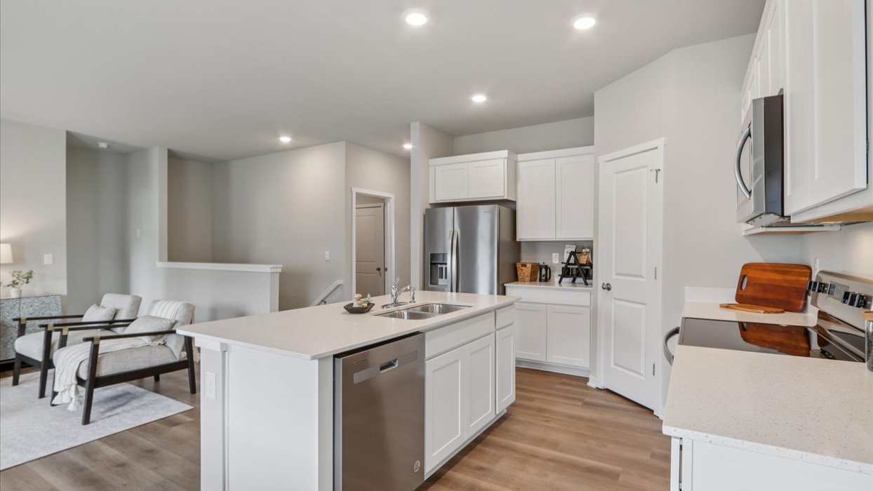 Kitchen with stainless steel appliances, quartz countertops, and white cabinetry