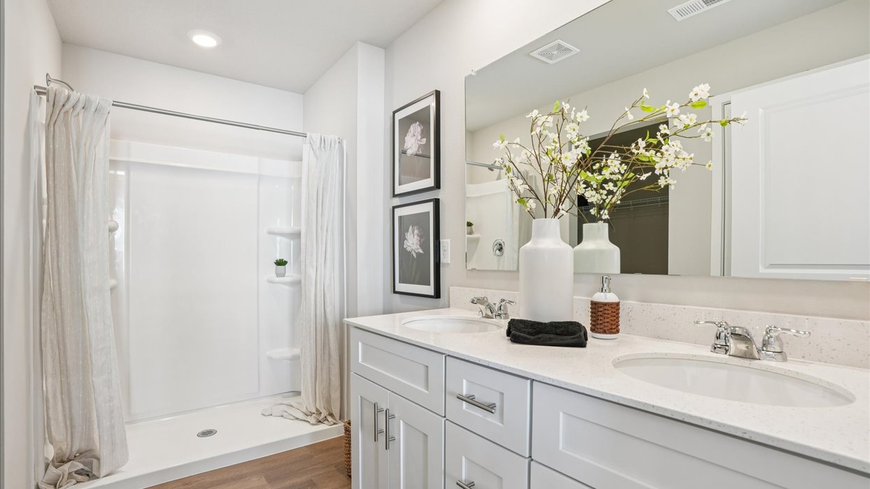 primary bathroom with large mirror and shower with dual sinks