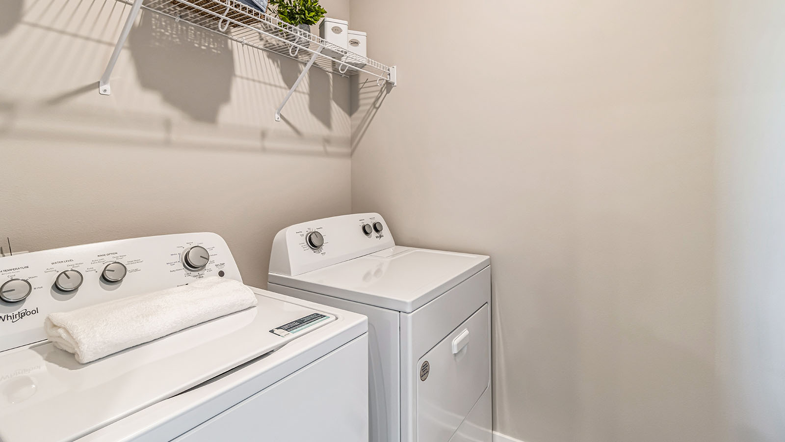 Dedicated laundry room with built-in shelving and utility connections.