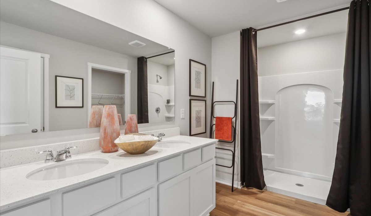 Spacious primary bathroom featuring dual vanities, modern fixtures, and a walk-in shower.