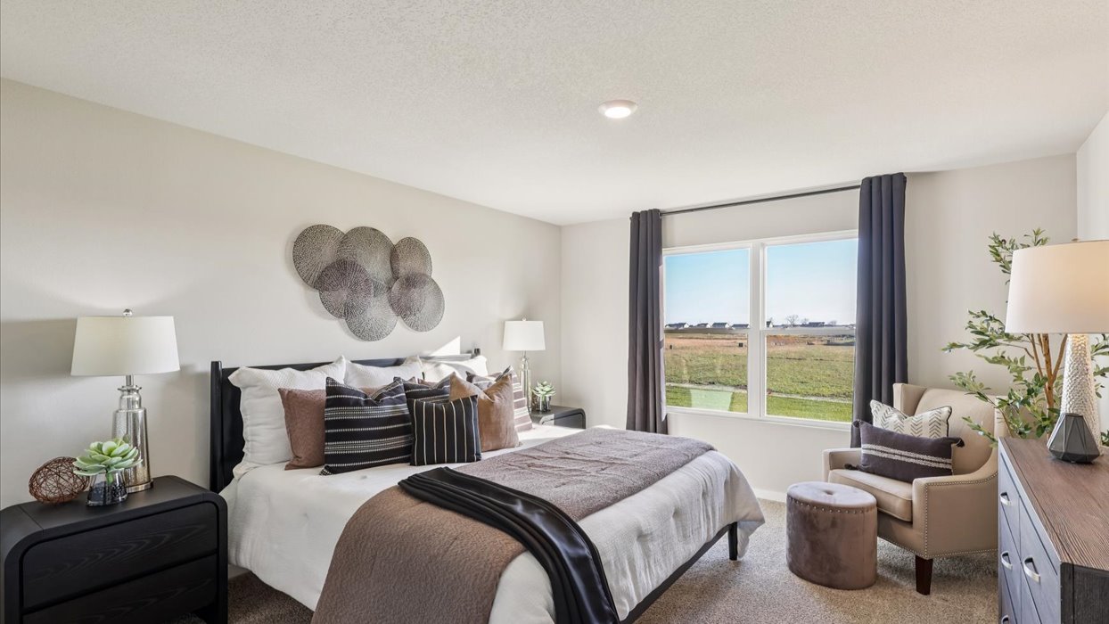 spacious primary bedroom with large window and overhead lighting