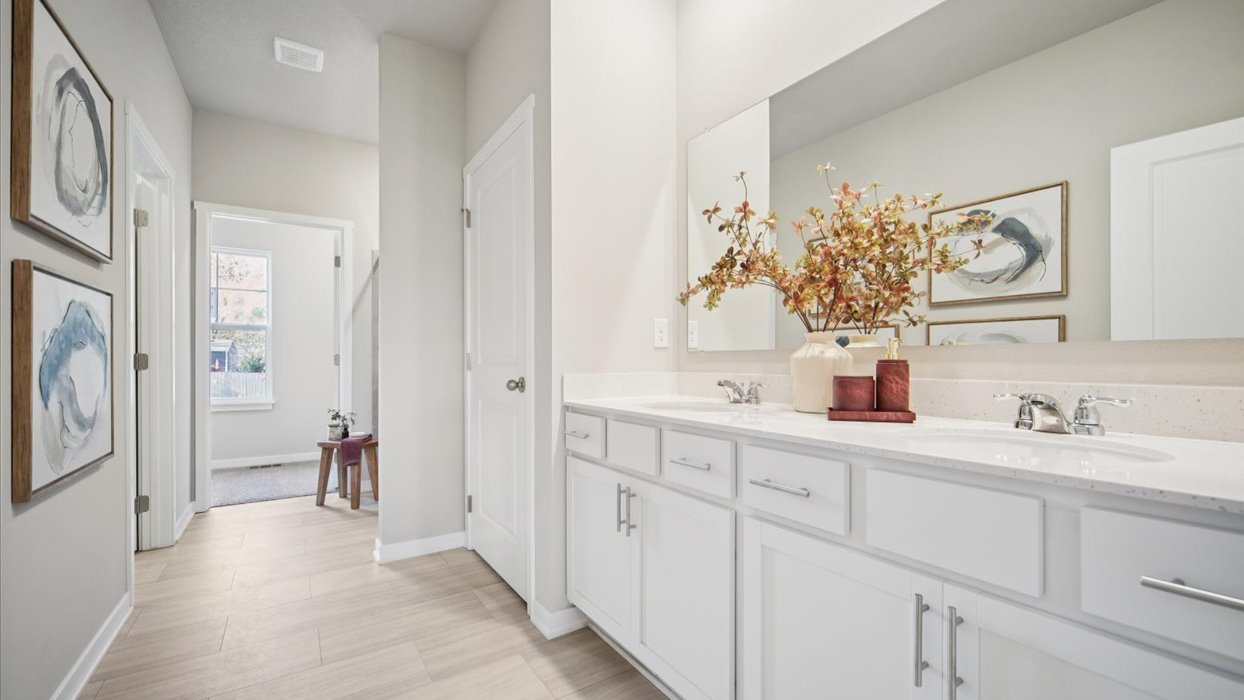 primary bathroom with large mirror and white cabinets