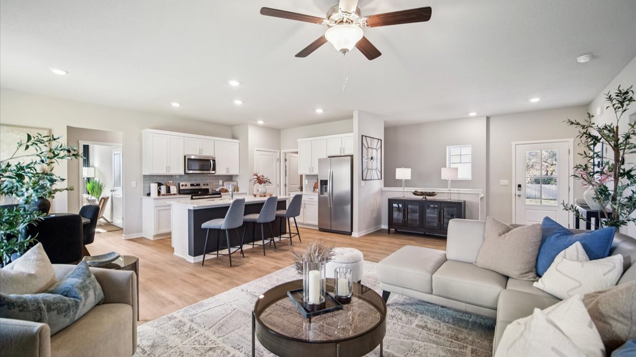 open concept living room with ceiling fan and kitchen