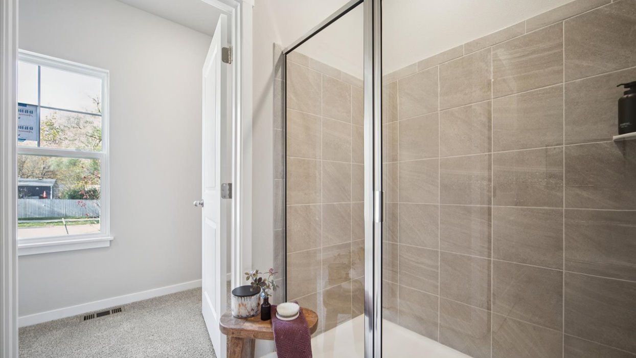 Owner’s ensuite bathroom featuring a walk-in shower and built-in storage shelving.