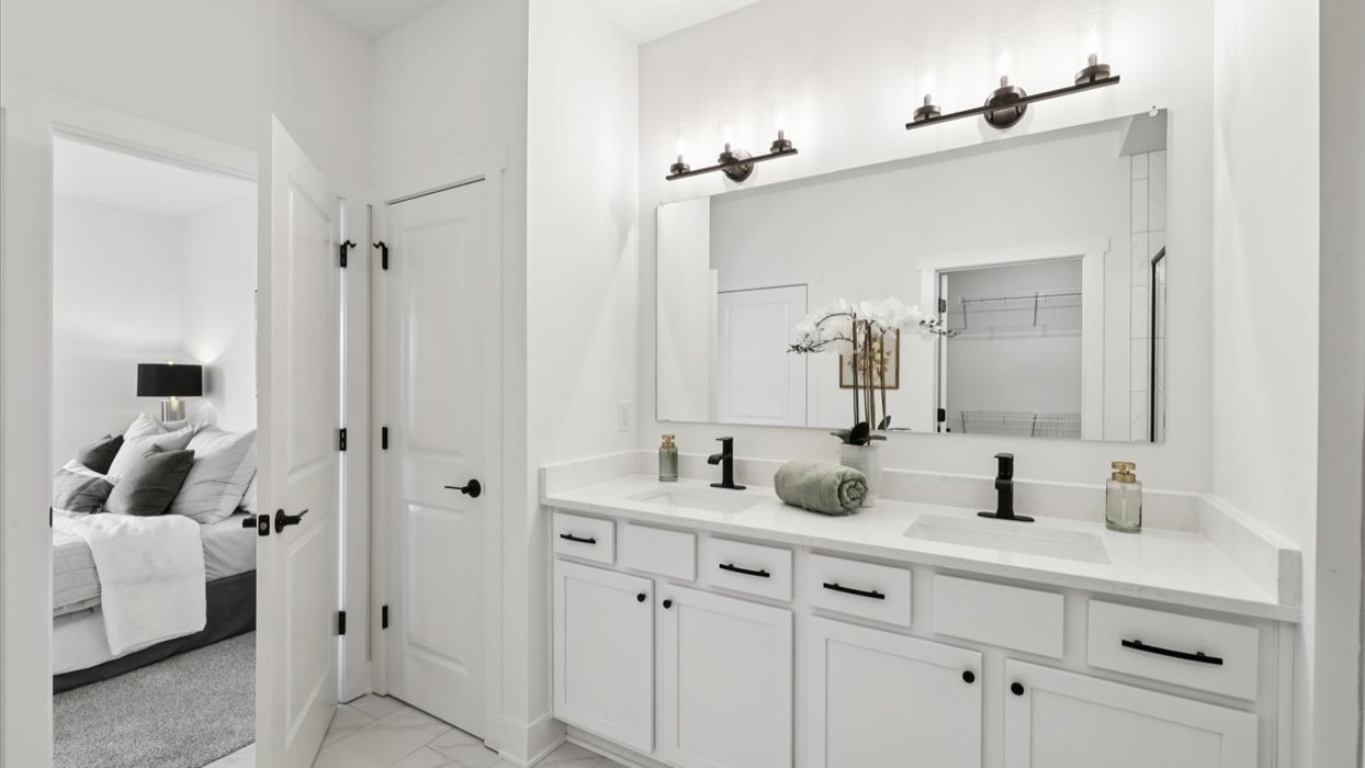 Spacious primary bathroom featuring dual vanities, modern fixtures, and a walk-in shower.
