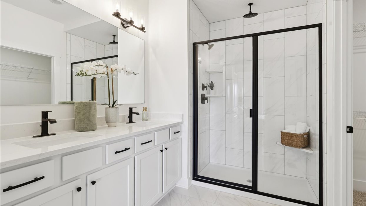 Spacious primary bathroom featuring dual vanities, modern fixtures, and a walk-in shower.