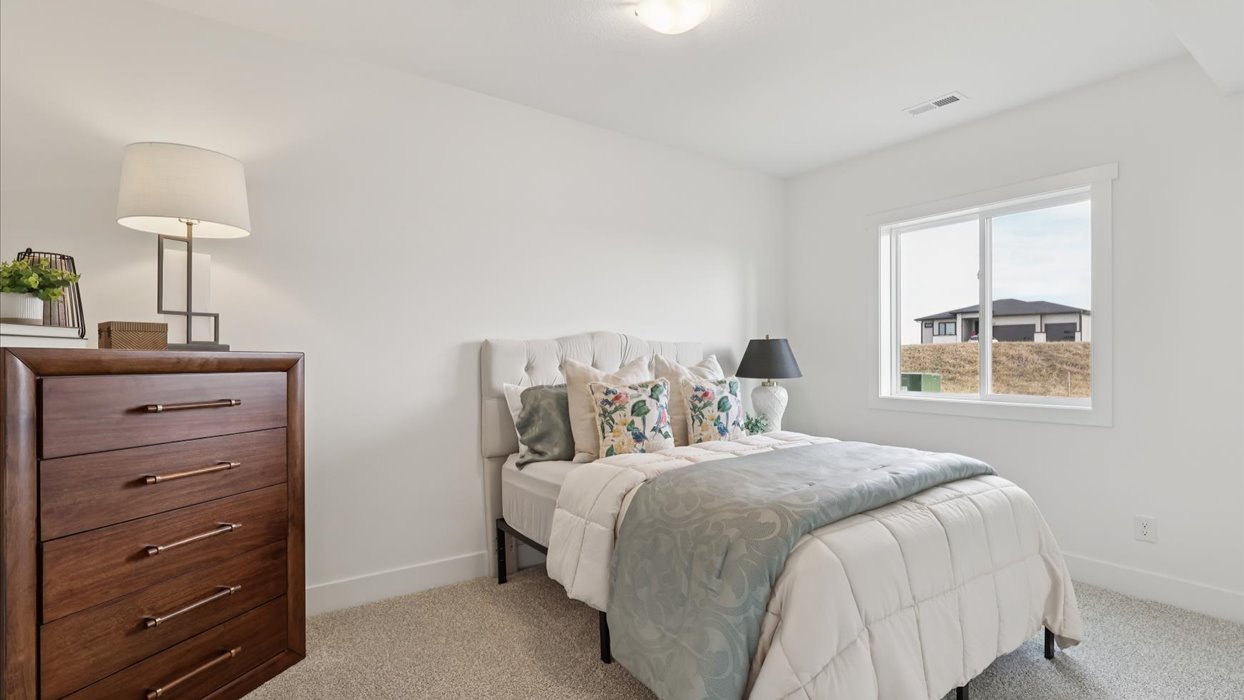 Private lower-level bedroom with natural light and functional storage space.