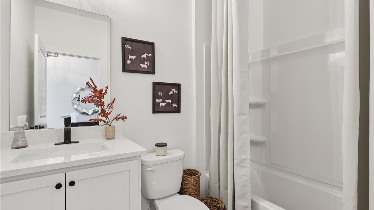 first bathroom with white cabinets and shower with bathtub