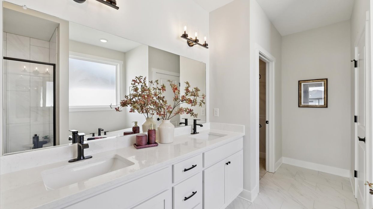 primary bathroom with large mirror and white cabinets