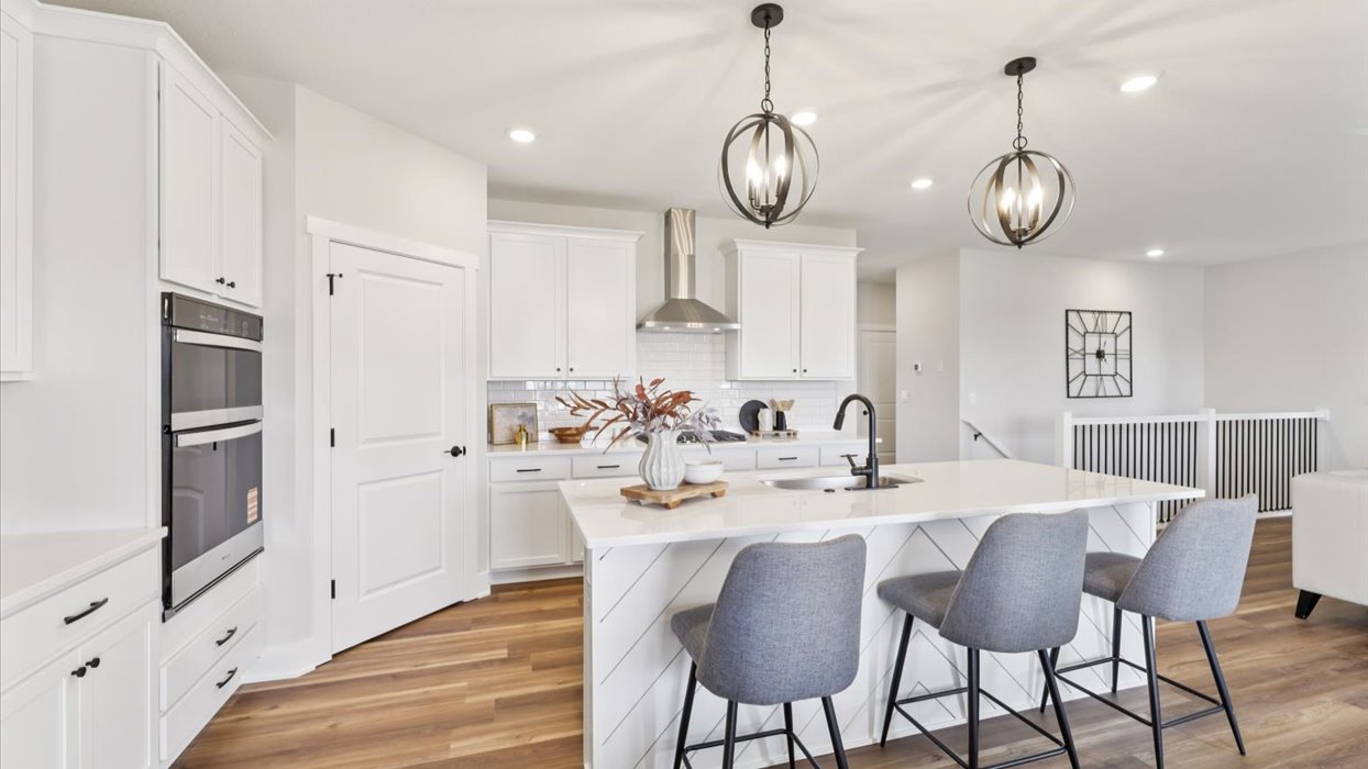 madison kitchen with light fixtures over the island with grey barstools