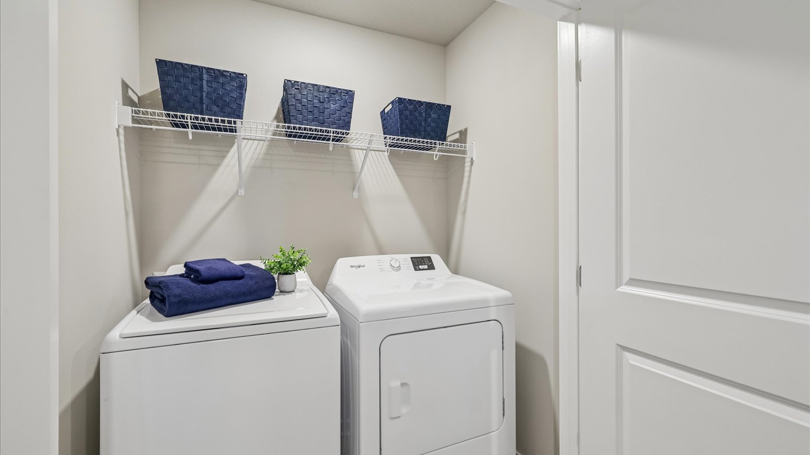 Cozy laundry space with natural light, a washer and dryer, and shelving for supplies.