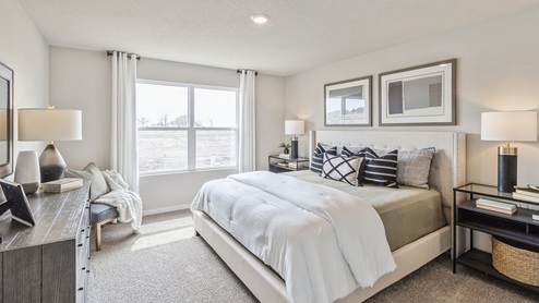 primary bedroom with large window and green bed with nightstands and dressser