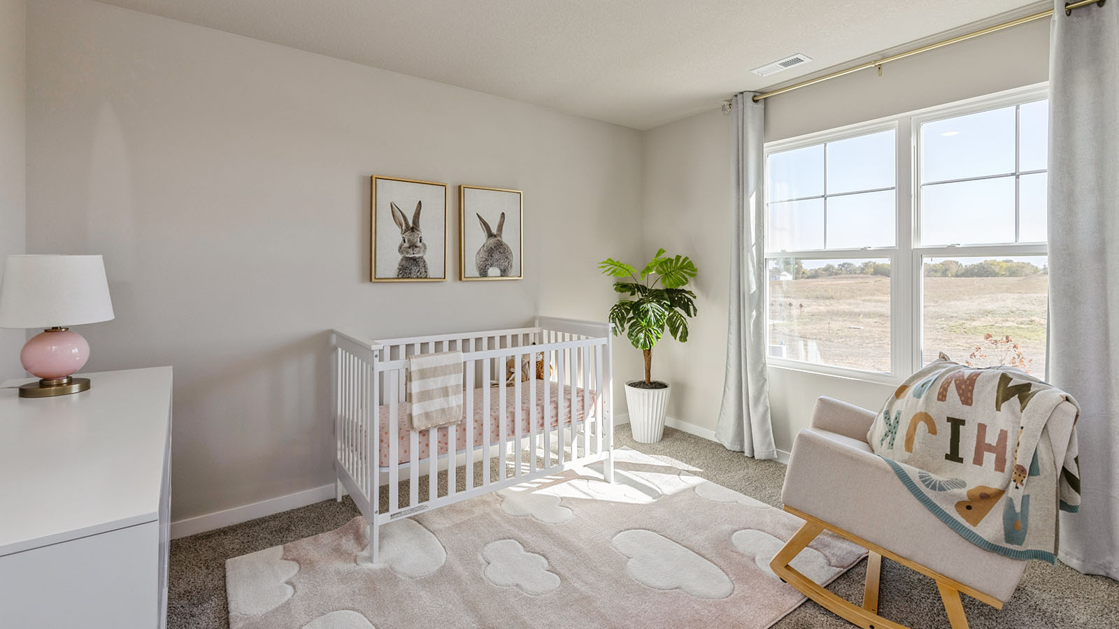 First bedroom staged as a nursery with crib and seating area