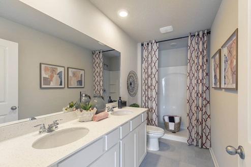 primary bathroom with dual sinks and white cabinets
