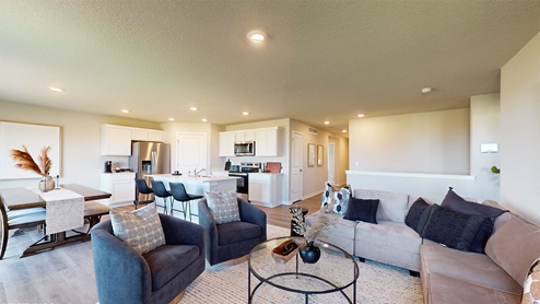 Living room with couch and chairs overlooking dining area and kitchen