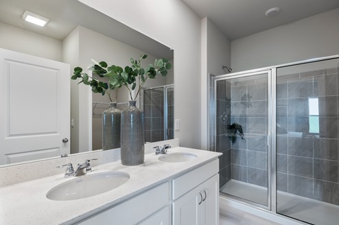 Primary bathroom with two sinks and glass shower doors