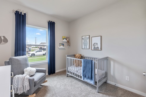 First bedroom staged as a kids nursery with grey crib