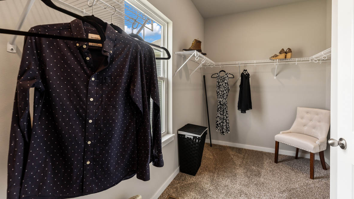Walk-in closet off primary bathroom with shelving and chair