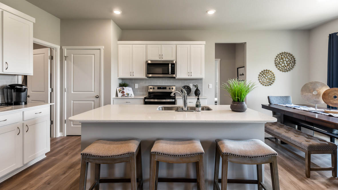 Kitchen with white island and brown barstools