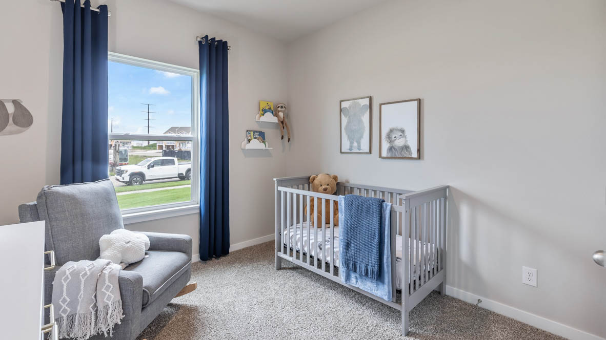 First bedroom staged as a kids nursery with grey crib