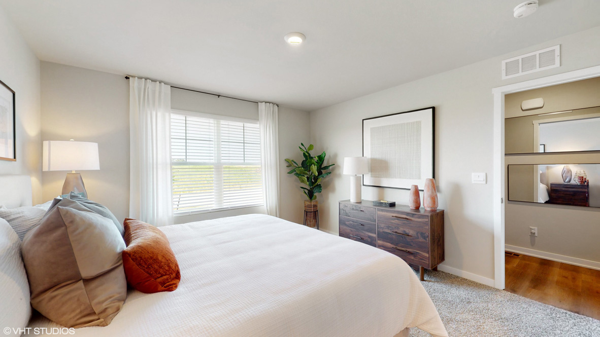 Primary bedroom with window and showing hallway