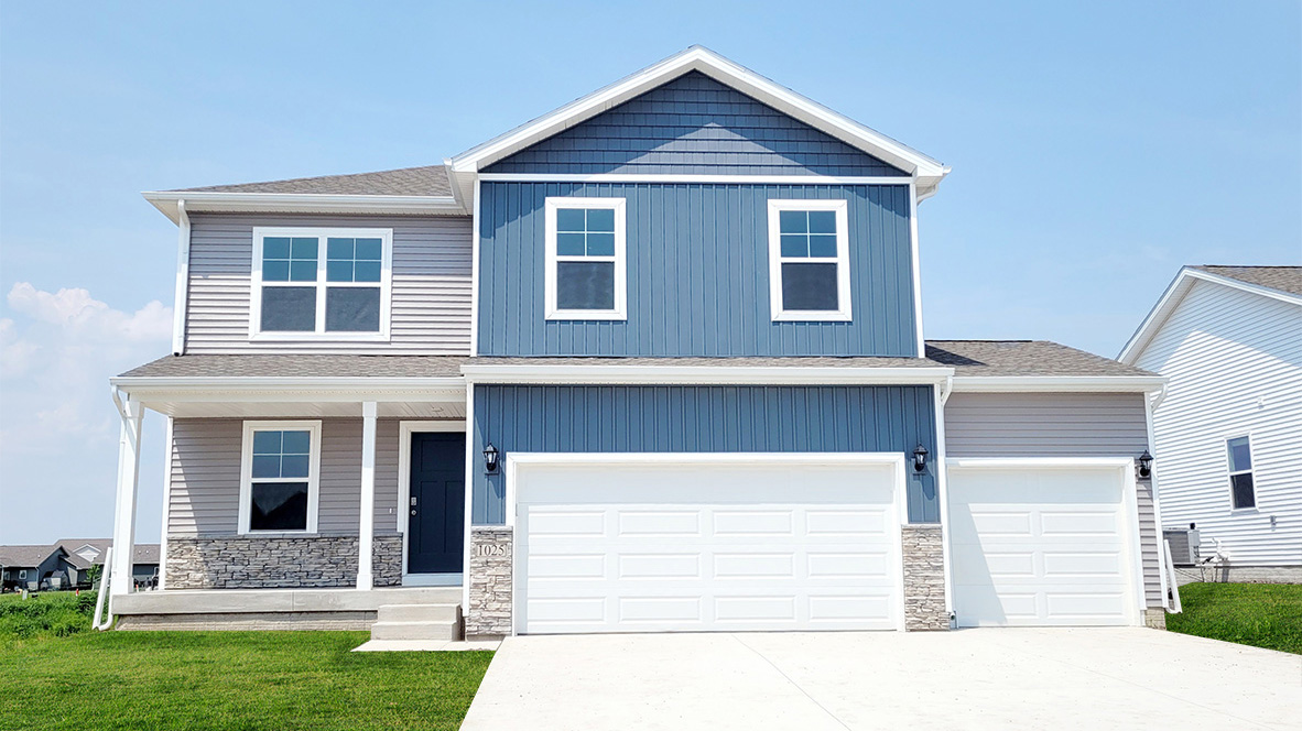 Exterior photo of the Bellhaven plan with blue and grey stone, a covered porch and a 3 car-garage
