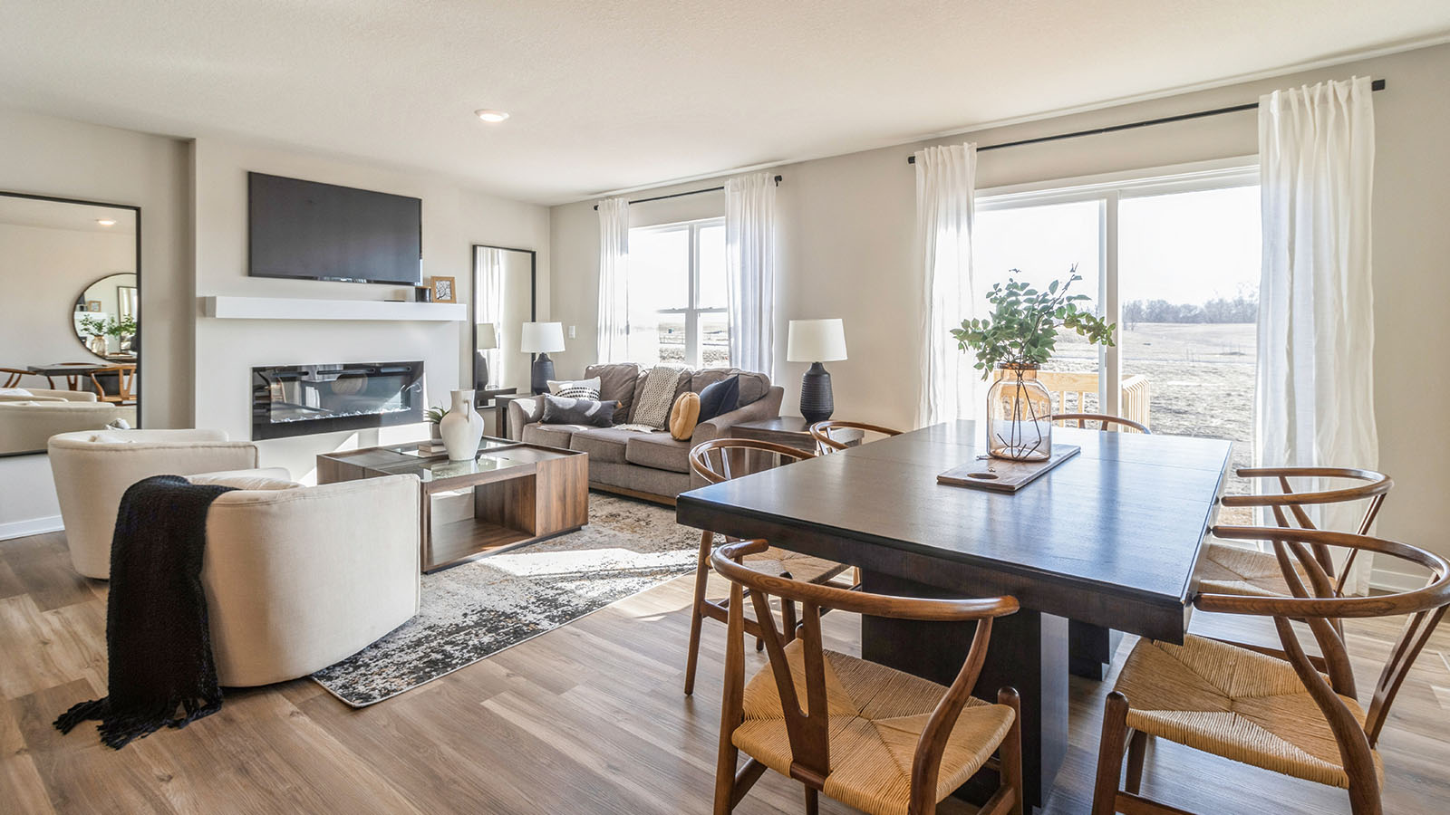 Dining area with black table and wood chairs overlooking spacious living room