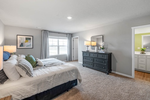 Large primary bedroom with carpeting and overhead lighting