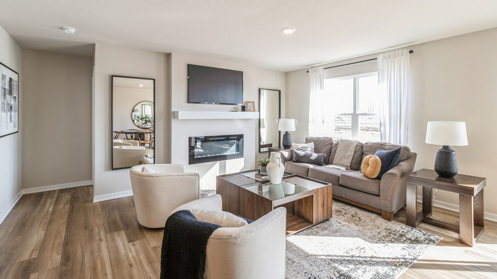 Spacious living room with large windows, electric fireplace, and natural light, open to the dining area in this New Build Home