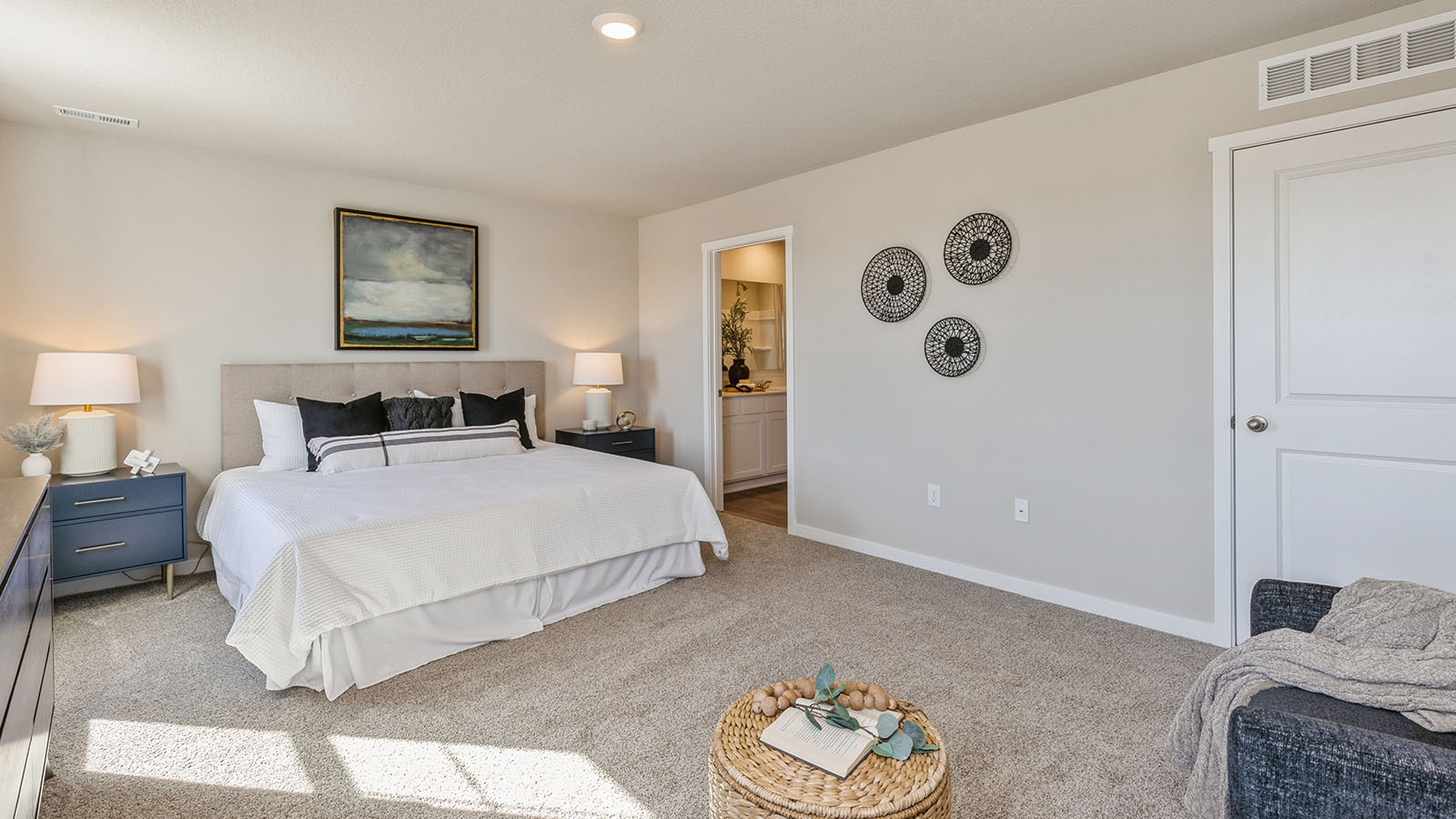 Spacious primary bedroom with karge white bed next to primary bathroom
