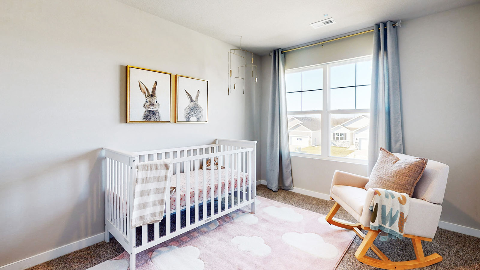 First bedroom staged as a nursery with crib and seating area