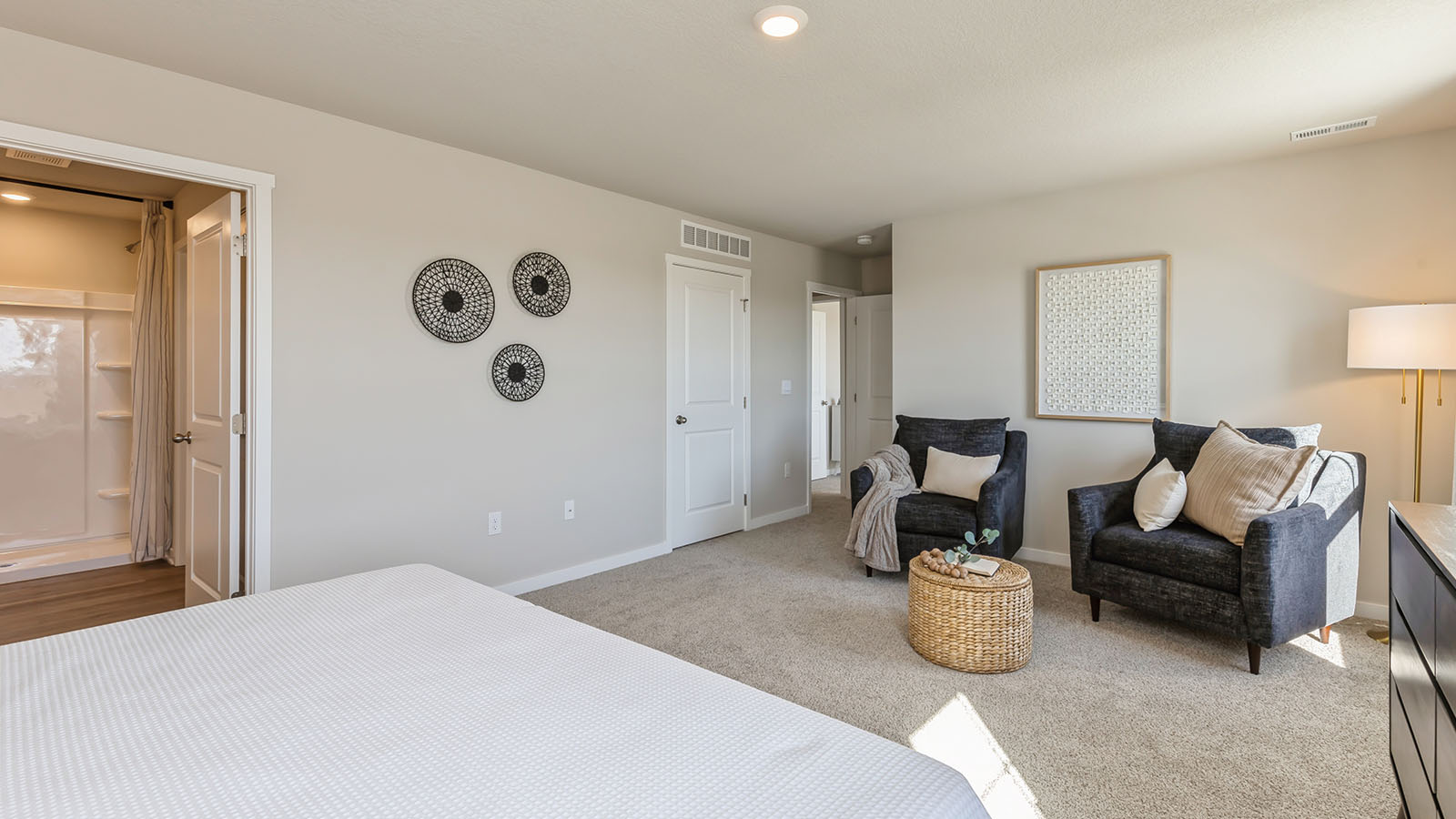 Bedroom featuring a large bed with white bedding and two black chairs.