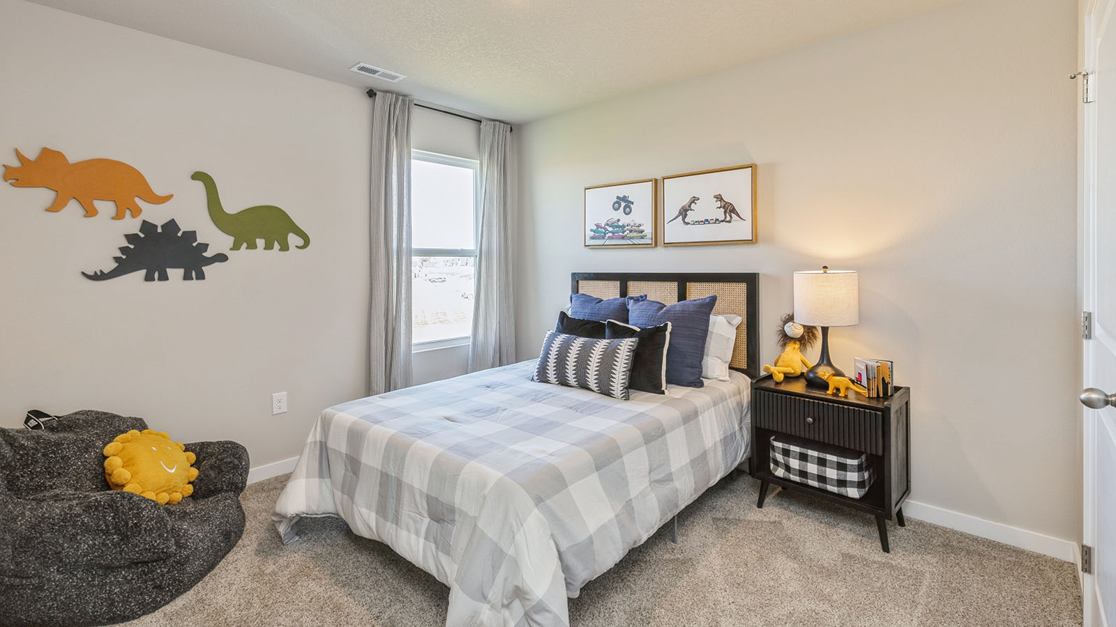 Bedroom featuring a bed with white and grey bedding, a black nightstand, and a window.