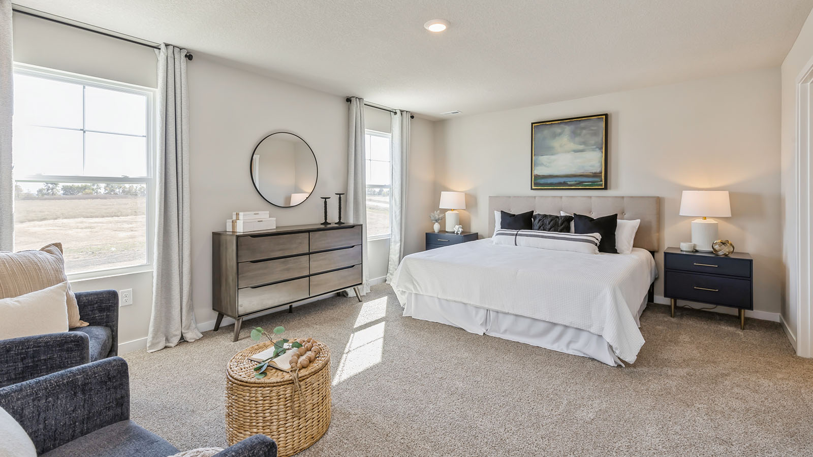 Bedroom featuring a large bed with white bedding, two nightstands and large windows.