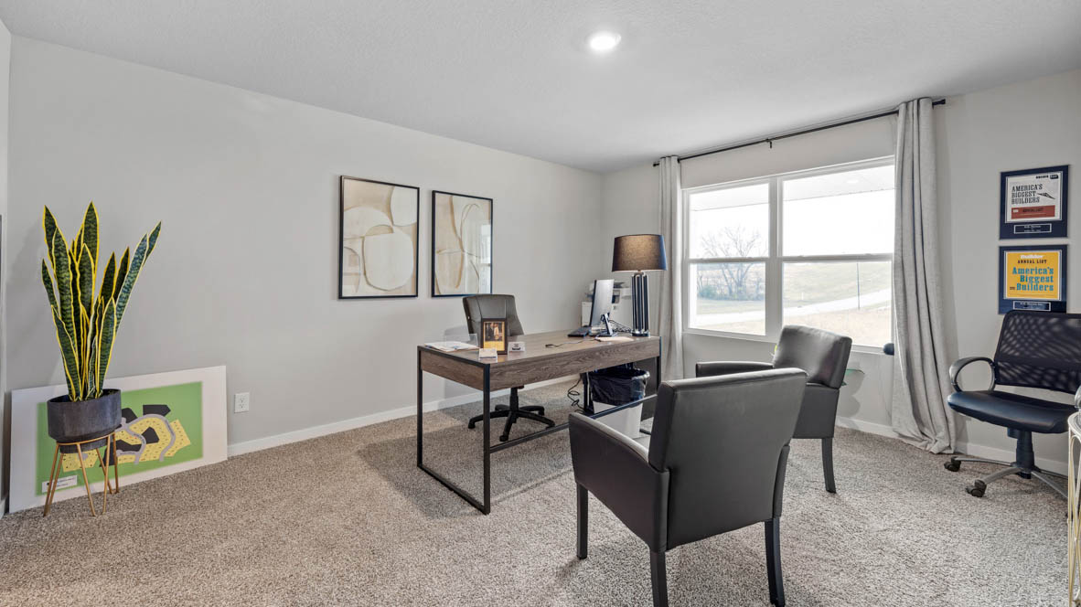 First bedroom staged as an office with a brown desk and two black chairs