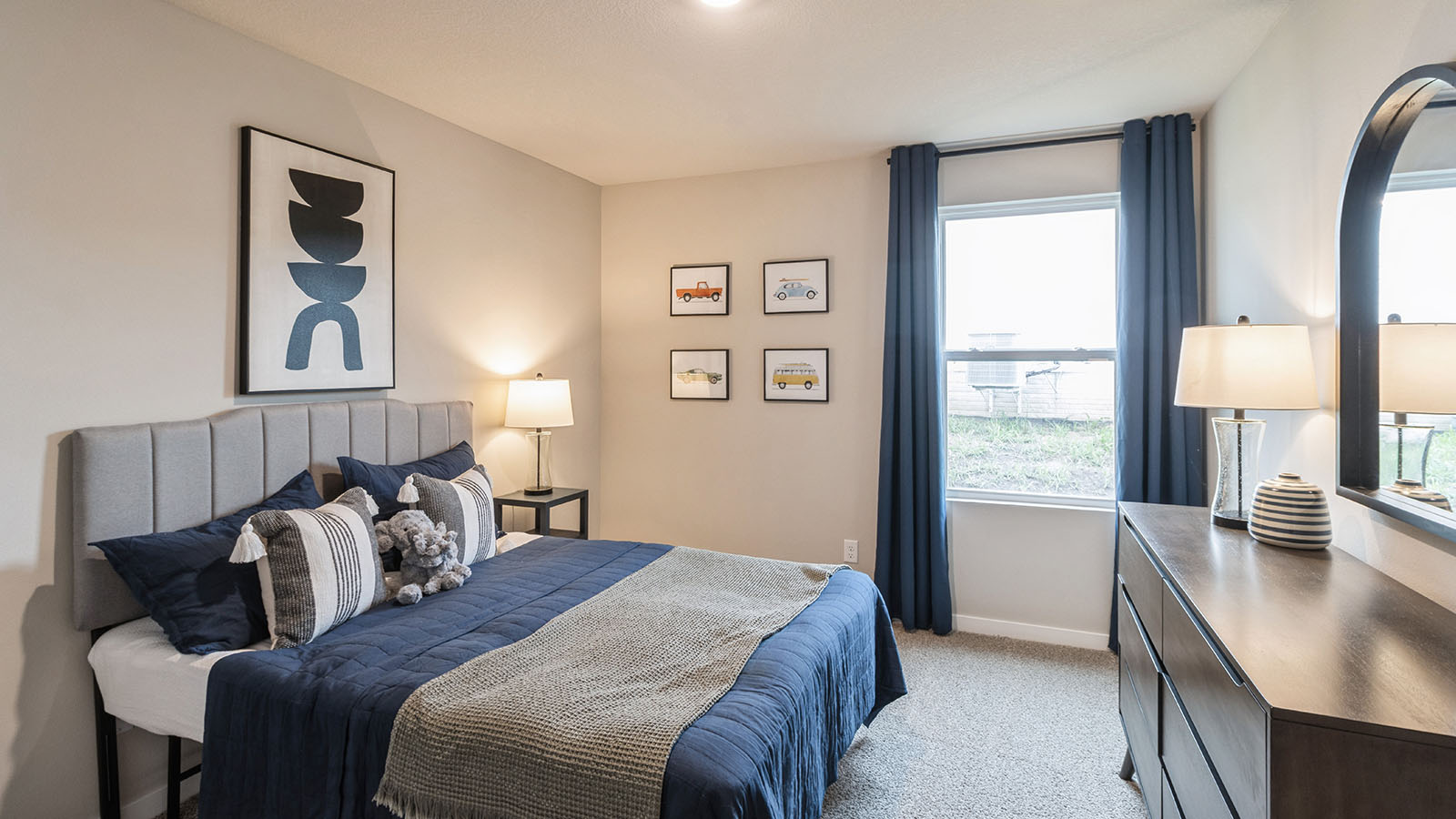 First bedroom with small window and blue bed with wood dresser