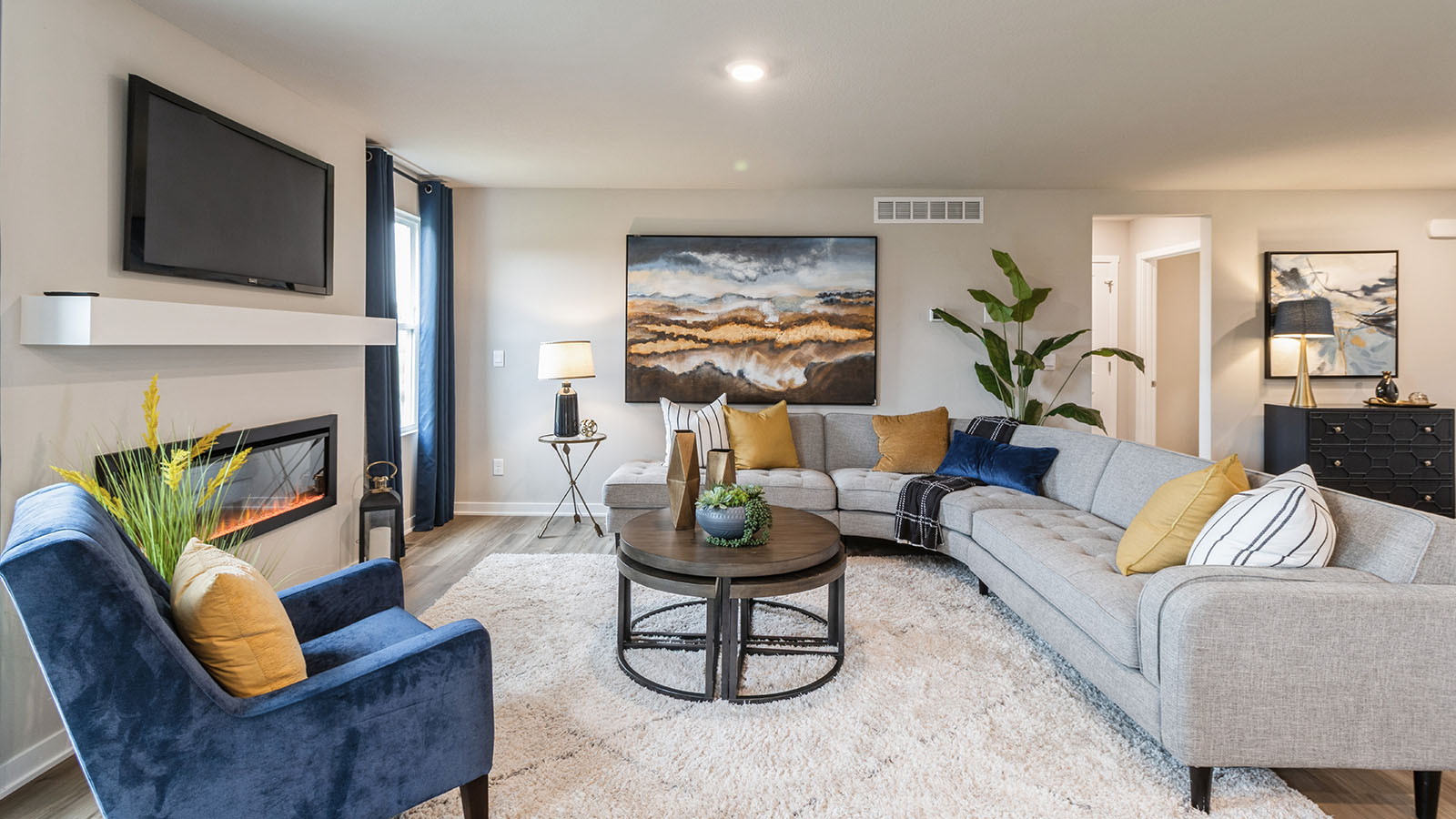Bright and colorful living room with  large grey sectional and blue armchair
