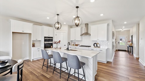 white kitchen with island and quartz countertops and pendant lighting